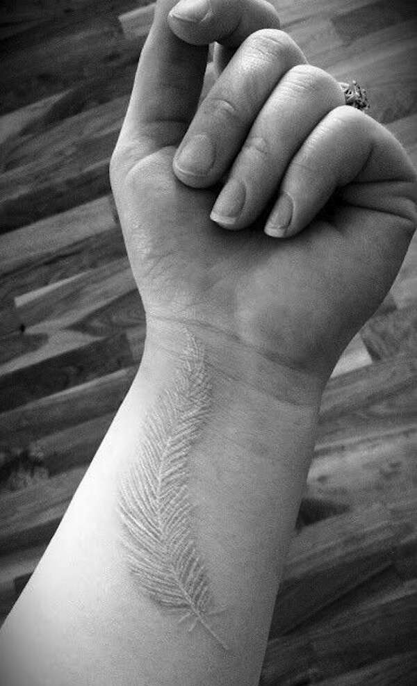 Tatuaje de pluma con tinta blanca